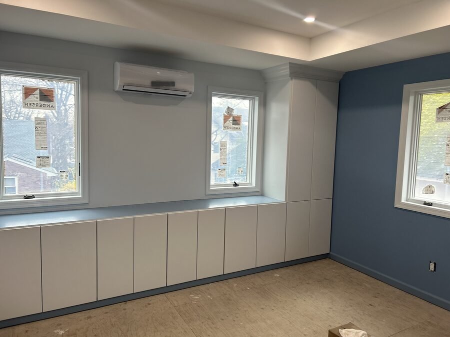 Room with blue accent wall, built-in base cabinets, and window trim