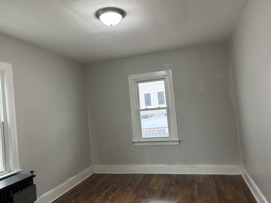 Clean finished gray room with window, trim, and dark floor