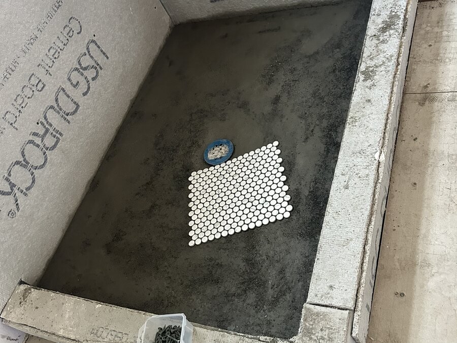 Diseño de piso de ducha con mosaico penny y ubicación de drenaje