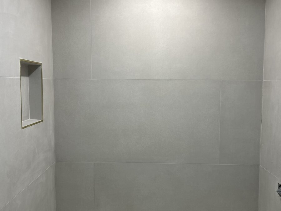 Pared de ducha de azulejo gris con nicho empotrado