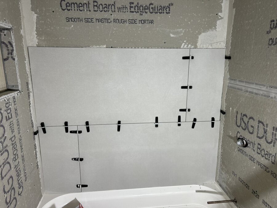 Instalación de azulejo alrededor de bañera con niveladores y panel impermeable