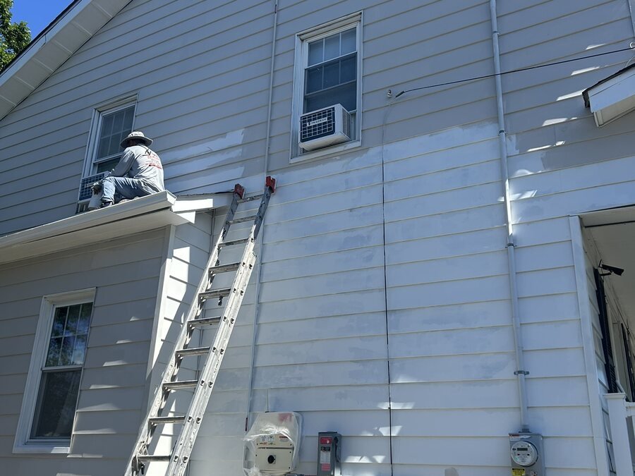 Pintor terminando el revestimiento exterior sobre un porche residencial