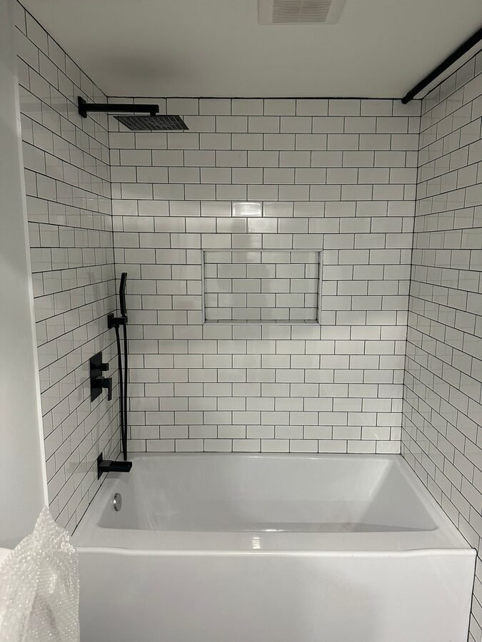 White subway tile shower wall with black shower fixture