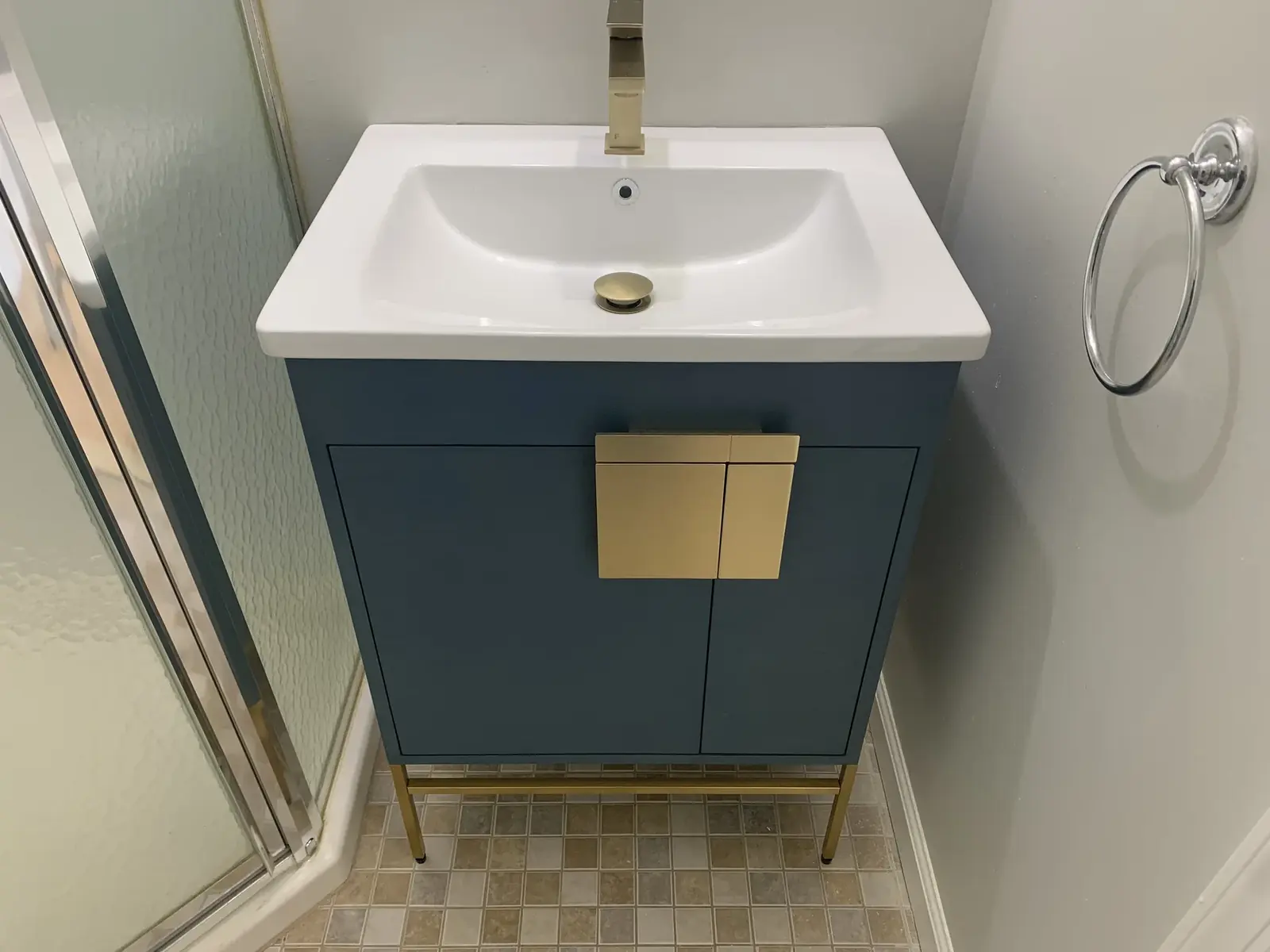 Bathroom vanity with blue cabinet, mirror, and tile floor