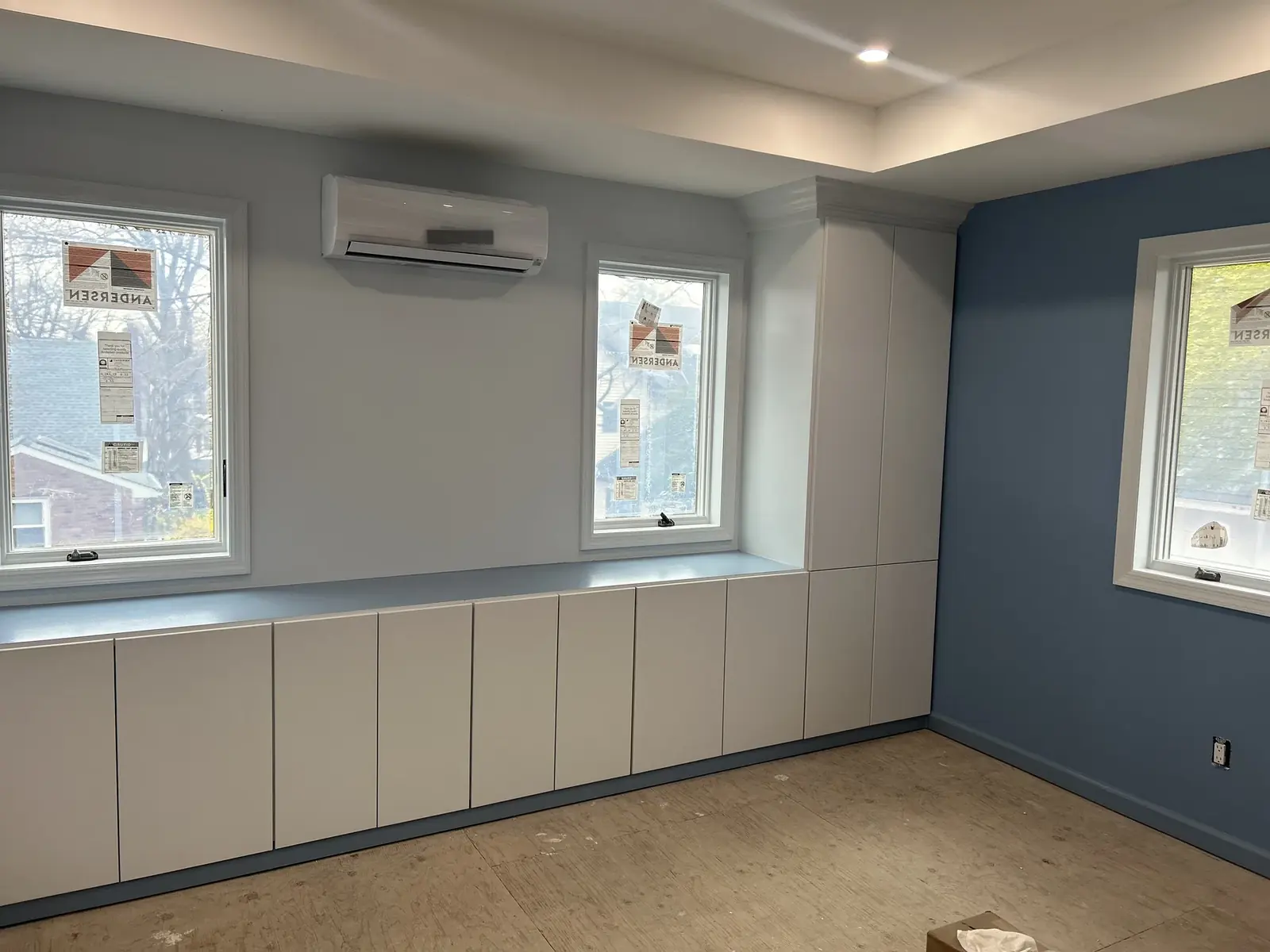 Room with blue accent wall, built-in base cabinets, and window trim