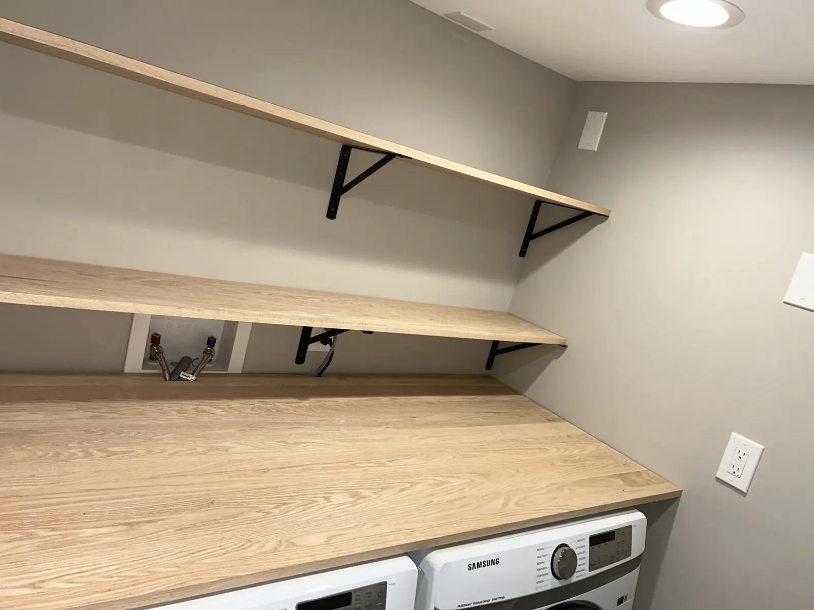 Laundry area with wood shelf, wall brackets, and washer and dryer