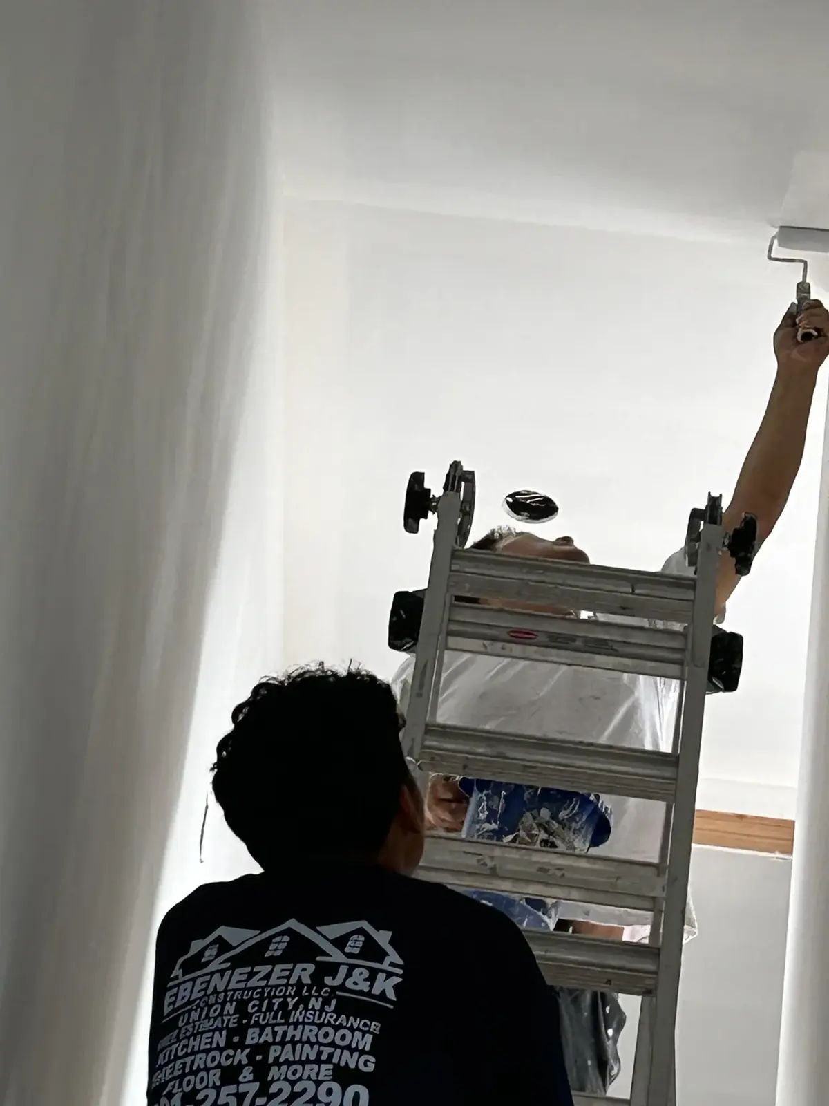 Worker painting or finishing a wall from a ladder